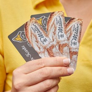 Bäcker Müller, drei Knusperkarten in der Hand der Verkäuferin (Nahaufnahme)